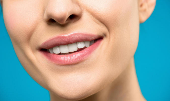 A close-up high-resolution photograph of a person smiling radiantly with perfectly aligned teeth.